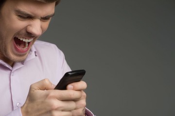 Angry young man holding a mobile phone